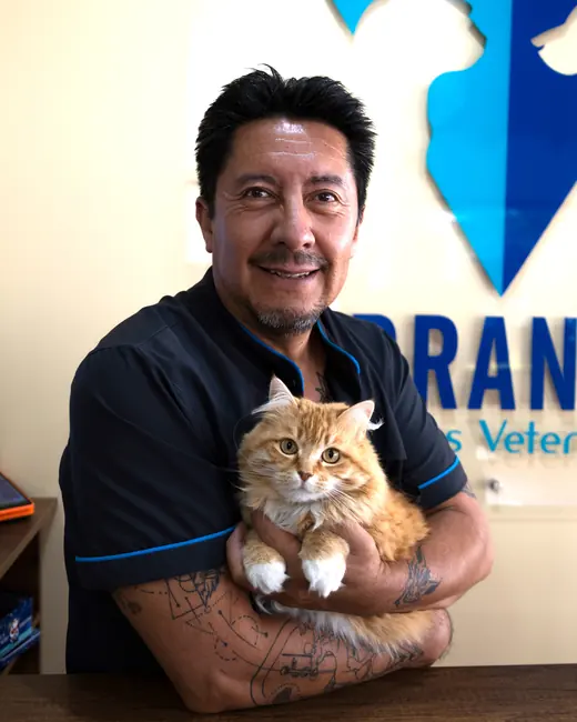 Un veterinario de Terranova junto a un perro grande, frente al letrero de la clínica.