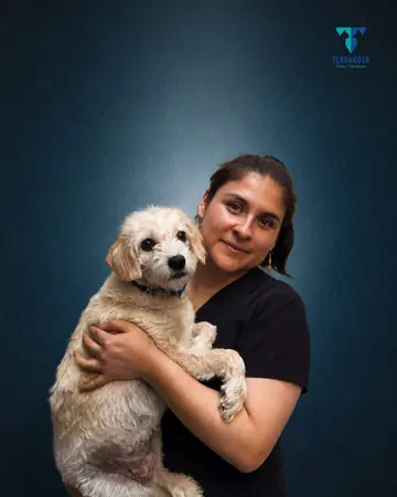 Retrato de Paola Almeida con un perro pequeño de pelo claro en brazos.